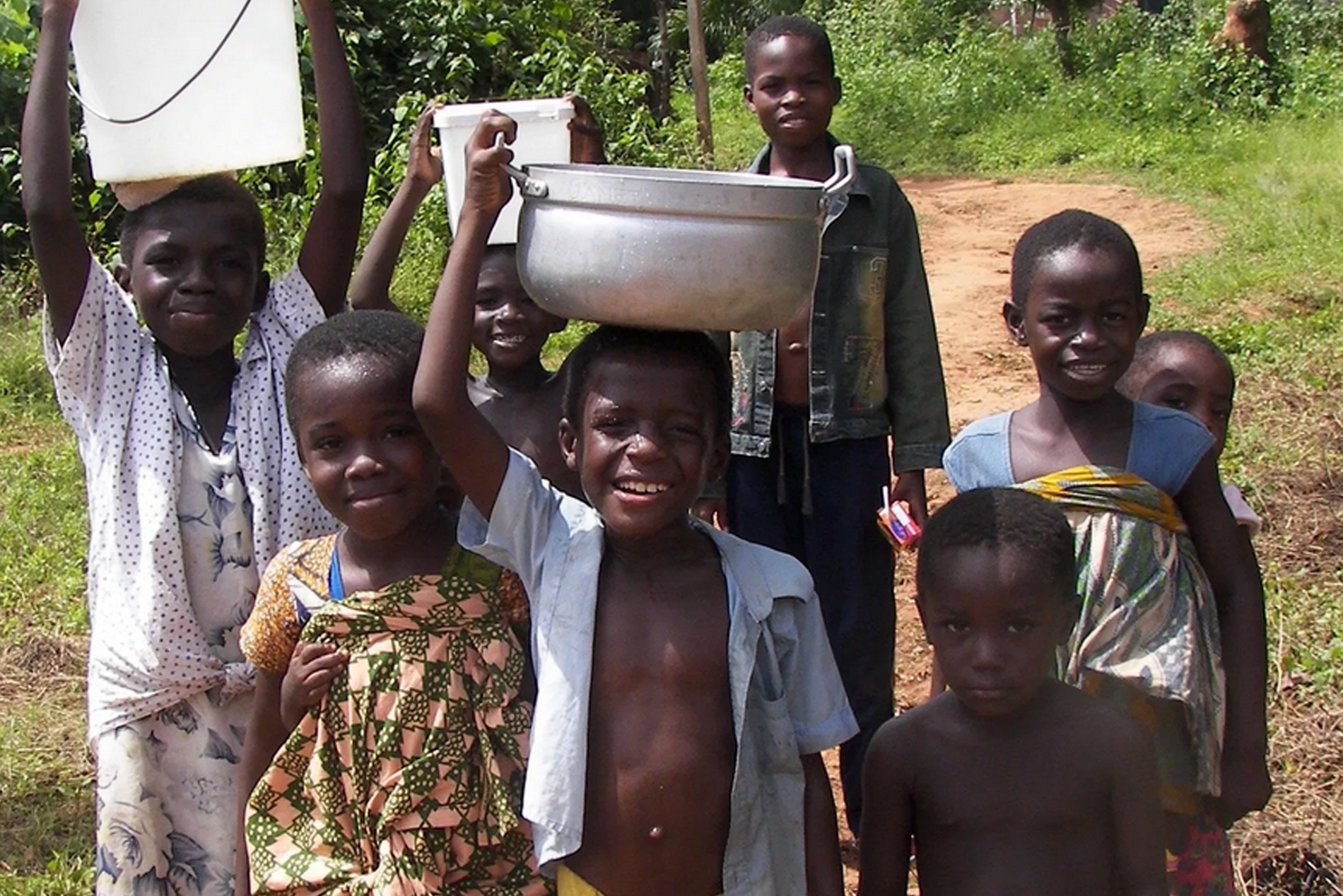 Children in Ghana carrying water in bowls and canisters