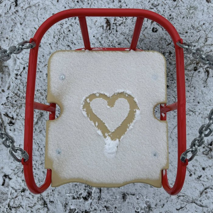 A swing in the snow with a heart drawn on the seat